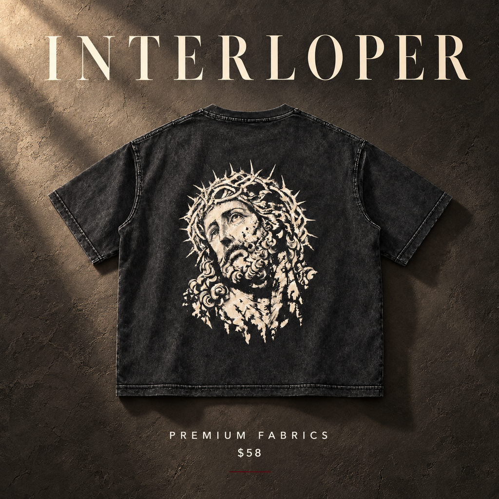 A black washed short-sleeve T-shirt shown from the back, featuring a large white graphic of Jesus with a crown of thorns. The shirt is displayed on a textured dark brown background with dramatic lighting, and the text 'INTERLOPER' appears at the top, 'PREMIUM FABRICS' at the bottom, and '$58' below.